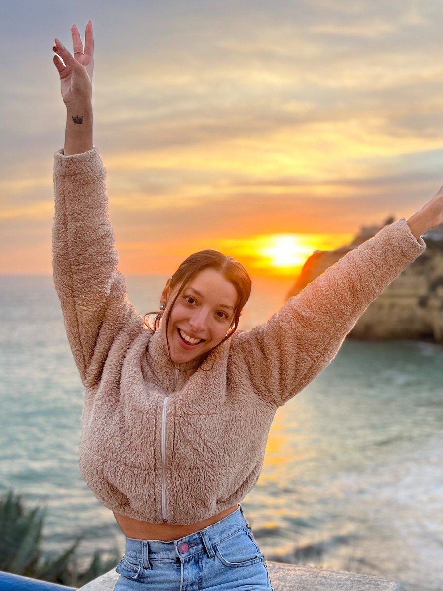 Antonella festejando frente al mar al atardecer